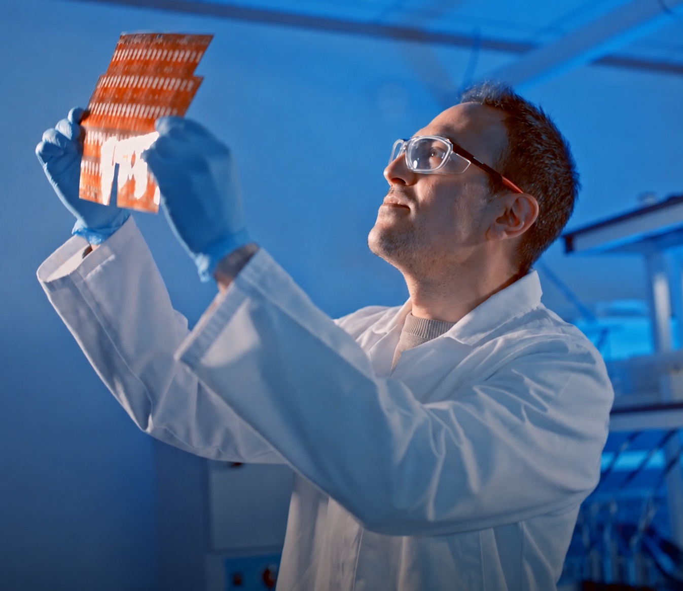 iGii scientist inspecting a flexible electrode sheet under lab lighting