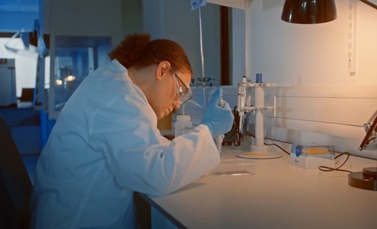 Researcher in a lab coat preparing battery samples at an iGii laboratory bench